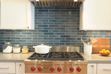Inspiration for a mid-sized transitional u-shaped medium tone wood floor enclosed kitchen remodel in San Francisco with an undermount sink, shaker cabinets, white cabinets, quartz countertops, blue backsplash, subway tile backsplash, stainless steel appliances and no island