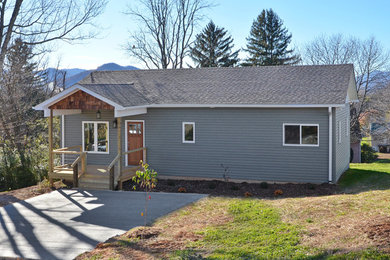 Example of a classic green one-story vinyl exterior home design in Other with a shingle roof