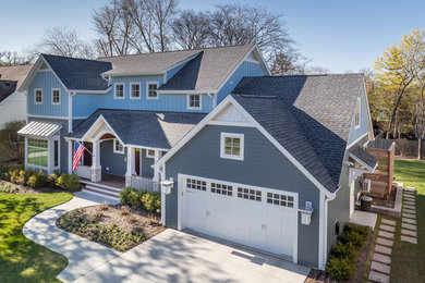 This is an example of a mid-sized arts and crafts two-storey blue house exterior in Chicago with concrete fiberboard siding, a gable roof and a shingle roof.