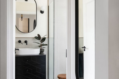 Medium sized contemporary bathroom in London with flat-panel cabinets, black cabinets, a wall mounted toilet, white tiles, ceramic tiles, white walls, ceramic flooring, a vessel sink, engineered stone worktops, multi-coloured floors, an open shower, multi-coloured worktops, a laundry area, a single sink and a freestanding vanity unit.