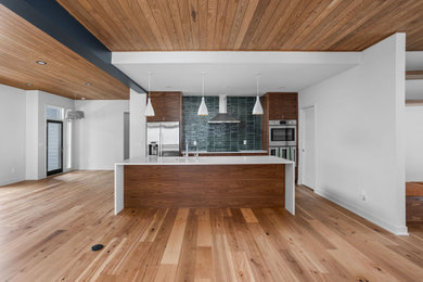Mid-century modern galley eat-in kitchen photo in Indianapolis with an undermount sink, flat-panel cabinets, dark wood cabinets, quartz countertops, green backsplash, porcelain backsplash, stainless steel appliances, an island and white countertops