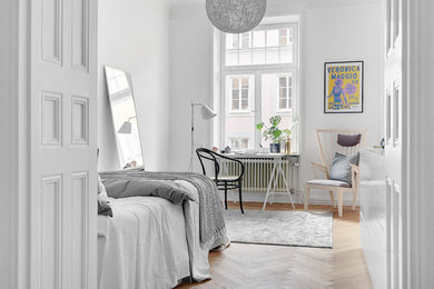 This is an example of a mid-sized scandinavian master bedroom in Stockholm with white walls and light hardwood floors.