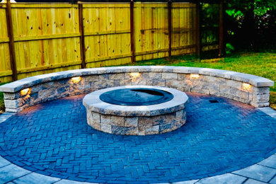 Inspiration for a mid-sized timeless backyard brick patio remodel in DC Metro with a fire pit and no cover