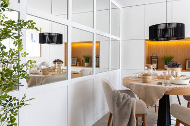 Foto di una sala da pranzo aperta verso il soggiorno moderna di medie dimensioni con pareti beige, parquet chiaro e pannellatura