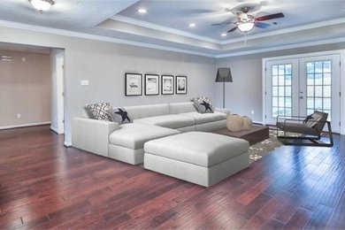 Example of a large trendy open concept dark wood floor and brown floor living room design in Houston with gray walls and no fireplace