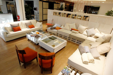 Foto de sala de estar tipo loft minimalista grande con paredes blancas, suelo de madera clara y televisor colgado en la pared