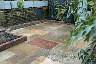 Photo of a small traditional back formal full sun garden wall for spring in Sussex with a retaining wall and natural stone paving.