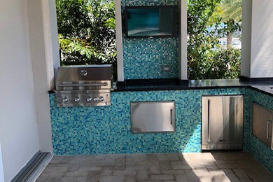 Patio kitchen - mid-sized contemporary backyard stone patio kitchen idea in Miami with a roof extension