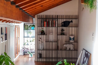 Immagine di un soggiorno contemporaneo di medie dimensioni e aperto con libreria, pareti bianche, pavimento in legno massello medio, TV nascosta e travi a vista
