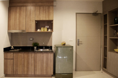 Inspiration for a small modern single-wall ceramic tile and beige floor wet bar remodel in New York with a drop-in sink, flat-panel cabinets, light wood cabinets, beige backsplash, glass tile backsplash and solid surface countertops