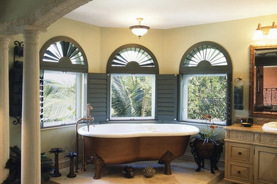 Example of a tuscan master marble floor and beige floor freestanding bathtub design in Tampa with brown cabinets, beige walls, a drop-in sink and marble countertops