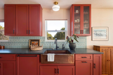 Mid-sized eclectic galley eat-in kitchen photo in Austin with a farmhouse sink, shaker cabinets, red cabinets, quartz countertops, blue backsplash, ceramic backsplash and black countertops
