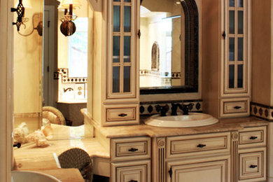 Example of a large classic master beige tile and stone tile travertine floor bathroom design in Richmond with a drop-in sink, raised-panel cabinets, distressed cabinets, marble countertops, a two-piece toilet and beige walls