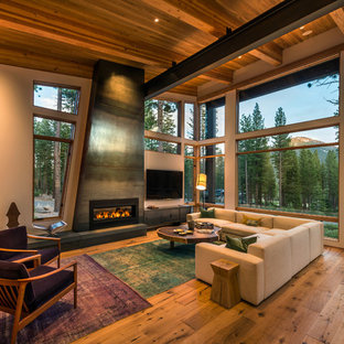 Idéer för ett modernt vardagsrum, med beige väggar, mellanmörkt trägolv, en bred öppen spis och en spiselkrans i metall