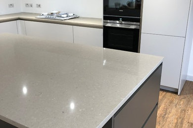 Inspiration for a medium sized contemporary l-shaped open plan kitchen in Buckinghamshire with an integrated sink, flat-panel cabinets, quartz worktops, integrated appliances, vinyl flooring and an island.