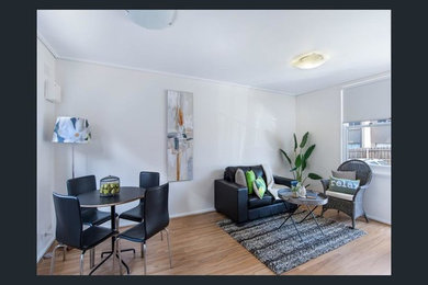 Photo of a small modern enclosed living room in Melbourne with white walls, light hardwood floors and a freestanding tv.