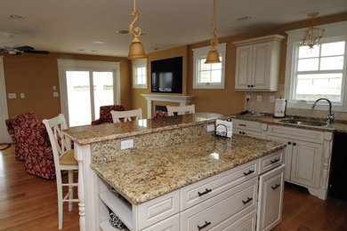 Mid-sized elegant u-shaped medium tone wood floor and brown floor open concept kitchen photo in Phoenix with granite countertops, beige backsplash, ceramic backsplash, an undermount sink, raised-panel cabinets, white cabinets, an island and stainless steel appliances