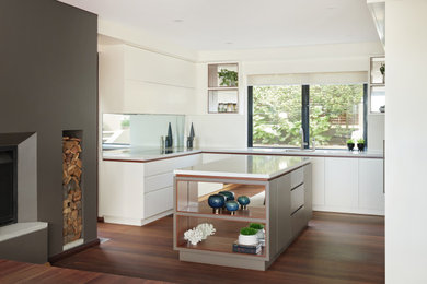 Photo of an u-shaped kitchen in Sydney with with island, white splashback and brown floor.