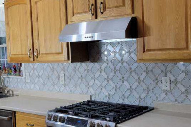 Example of a mid-sized eclectic l-shaped dark wood floor, brown floor and exposed beam enclosed kitchen design with a farmhouse sink, flat-panel cabinets, gray cabinets, quartz countertops, gray backsplash, glass tile backsplash, white appliances, an island and beige countertops