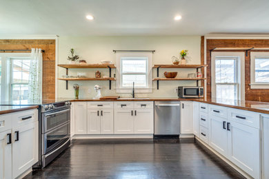 Inspiration for a mid-sized eclectic u-shaped dark wood floor and black floor eat-in kitchen remodel in Dallas with a double-bowl sink, shaker cabinets, white cabinets, wood countertops, stainless steel appliances and a peninsula