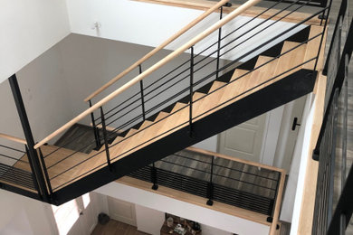Foto de escalera curva contemporánea sin contrahuella con escalones de madera y barandilla de metal