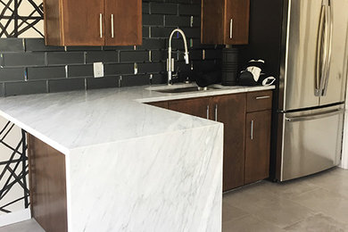 Mid-sized trendy l-shaped cement tile floor and gray floor eat-in kitchen photo in Austin with an undermount sink, flat-panel cabinets, dark wood cabinets, marble countertops, white backsplash, glass tile backsplash, black appliances, a peninsula and white countertops
