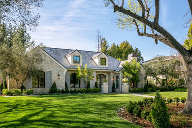 Inspiration for a transitional beige two-story stone house exterior remodel in Los Angeles with a shingle roof