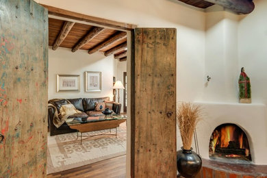 Living room - large southwestern formal and enclosed light wood floor and brown floor living room idea in Albuquerque with beige walls, no fireplace, a plaster fireplace and no tv