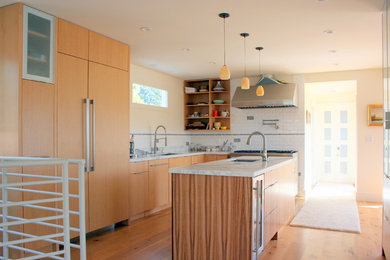 Example of a large trendy l-shaped medium tone wood floor eat-in kitchen design in San Francisco with an undermount sink, flat-panel cabinets, light wood cabinets, marble countertops, white backsplash, ceramic backsplash, stainless steel appliances and an island