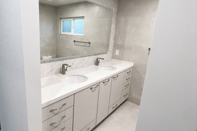Photo of a small contemporary ensuite bathroom in San Francisco with flat-panel cabinets, white cabinets, a built-in shower, a bidet, grey tiles, marble tiles, grey walls, porcelain flooring, a submerged sink, engineered stone worktops, grey floors, a sliding door, white worktops, a wall niche, double sinks and a built in vanity unit.