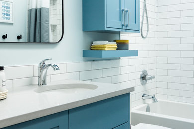 Mid-sized transitional kids' white tile gray floor and single-sink bathroom photo in Calgary with shaker cabinets, blue cabinets, blue walls, an undermount sink, quartz countertops, gray countertops and a niche