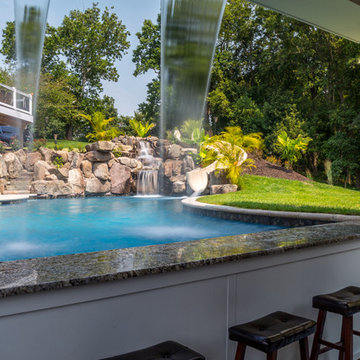 Custom pool with rock waterfalls, water slide & swim up pool bar.