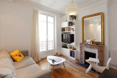 Cette image montre une salle de séjour design de taille moyenne et fermée avec une bibliothèque ou un coin lecture, un mur blanc, parquet clair, une cheminée standard, un manteau de cheminée en pierre et un téléviseur encastré.