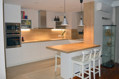 Foto de cocina nórdica grande con fregadero sobremueble, armarios con paneles lisos, puertas de armario blancas, encimera de laminado, salpicadero marrón, salpicadero de madera, electrodomésticos de acero inoxidable, suelo de baldosas de cerámica, península, suelo marrón y encimeras marrones
