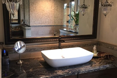 Design ideas for a large mediterranean master bathroom in Los Angeles with beige walls, a vessel sink, beige floor, raised-panel cabinets, dark wood cabinets, a corner shower, beige tile, granite benchtops and an open shower.