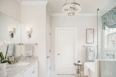 Traditional bathroom in Charlotte with raised-panel cabinets, white cabinets, a freestanding tub, a two-piece toilet, gray tile, grey walls, porcelain floors, an undermount sink, granite benchtops, white floor and white benchtops.