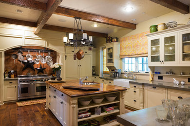 This is an example of a large traditional u-shaped eat-in kitchen in Sacramento with a farmhouse sink, recessed-panel cabinets, white cabinets, stainless steel appliances, dark hardwood floors, with island, brown floor and concrete benchtops.