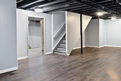 Example of a mid-sized minimalist underground laminate floor and brown floor basement design in Detroit with gray walls and no fireplace