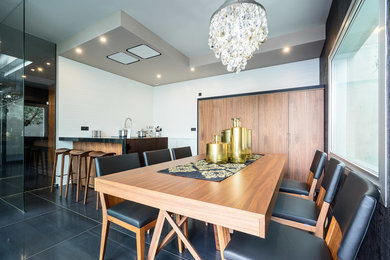 Modelo de comedor de cocina minimalista grande con paredes blancas, suelo de baldosas de porcelana y suelo negro