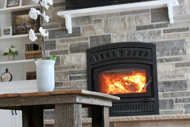 Example of a mid-sized classic open concept brown floor living room design in Toronto with a wood stove, a stone fireplace and a wall-mounted tv