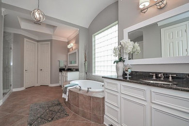 Inspiration for a transitional porcelain tile drop-in bathtub remodel in Houston with raised-panel cabinets and gray walls