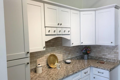 Bild på ett mellanstort vintage kök, med en dubbel diskho, luckor med infälld panel, vita skåp, granitbänkskiva, grått stänkskydd, stänkskydd i stenkakel, rostfria vitvaror och en köksö