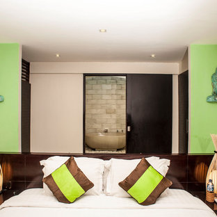 Esempio di una camera degli ospiti etnica di medie dimensioni con pareti verdi, pavimento in cemento e pavimento beige