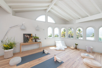 Design ideas for an expansive beach style home yoga studio in Los Angeles with white walls, light hardwood flooring, brown floors and exposed beams.