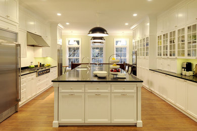 Large transitional galley kitchen photo in New York with an undermount sink, flat-panel cabinets, white cabinets, quartz countertops, black backsplash, stainless steel appliances and an island