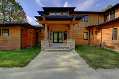 Mid-sized contemporary brown two-story wood house exterior idea in Other with a hip roof and a metal roof