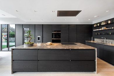 Contemporary kitchen in Surrey with an undermount sink, flat-panel cabinets, dark wood cabinets, grey splashback, with island, beige floor, grey benchtop and panelled appliances.