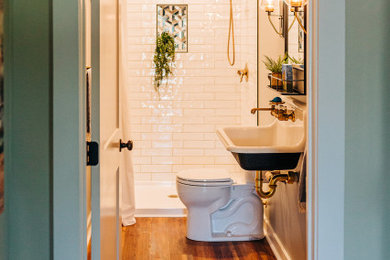 Small farmhouse 3/4 white tile and ceramic tile vinyl floor, brown floor and single-sink bathroom photo in Other with black cabinets, a two-piece toilet, gray walls, a wall-mount sink and a floating vanity