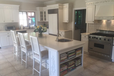 Inspiration for a mid-sized timeless l-shaped ceramic tile and gray floor eat-in kitchen remodel in New York with a drop-in sink, raised-panel cabinets, white cabinets, quartzite countertops, white backsplash, ceramic backsplash, stainless steel appliances and an island
