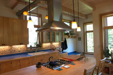 Eat-in kitchen - mid-sized craftsman l-shaped porcelain tile and beige floor eat-in kitchen idea in Other with a double-bowl sink, flat-panel cabinets, light wood cabinets, wood countertops, gray backsplash, stone tile backsplash, stainless steel appliances, an island and blue countertops